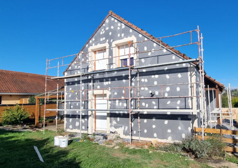 Maison sous échafaudage pendant la pose de panneaux d'isolation par l'extérieur