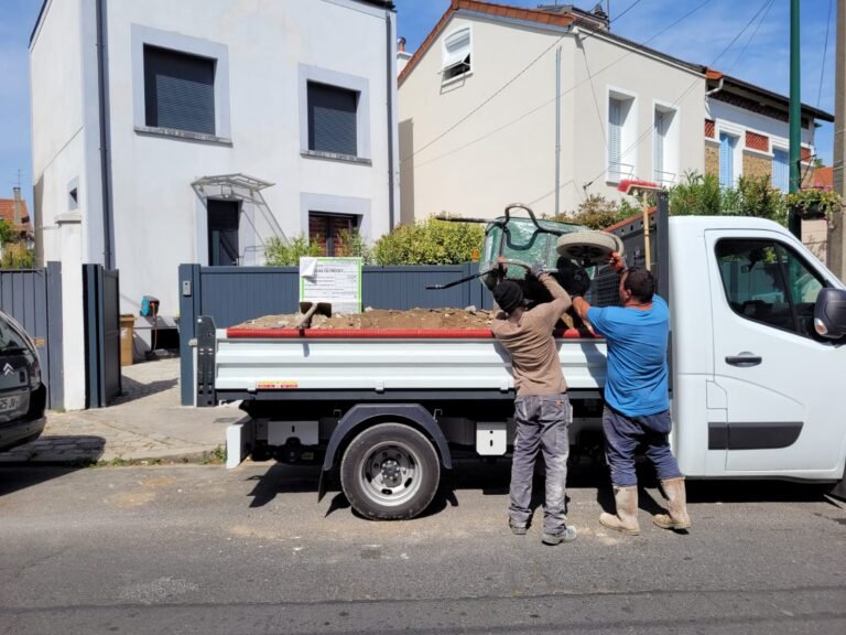 Deux compagnons de Toki France déchargent une bétonnière d'un camion-benne